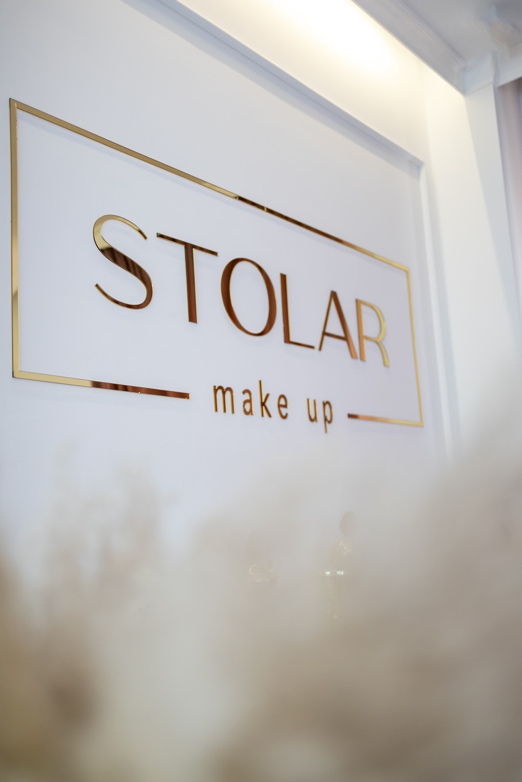 Złoty szyld STOLAR make up nad dekoracją z pampasów